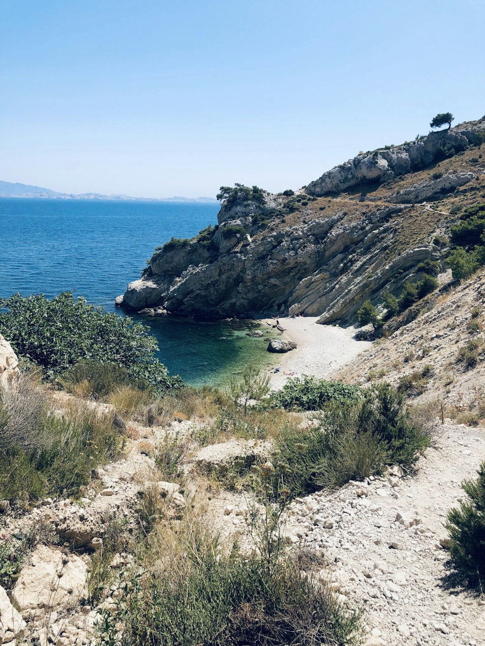 a rocky beach with a body of water in the background