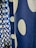 A close-up view of a blue fabric featuring large white polka dots in a vertical pattern. The fabric texture is visible, lending a tactile quality to the image. The polka dots vary slightly in size and are evenly spaced across the fabric.