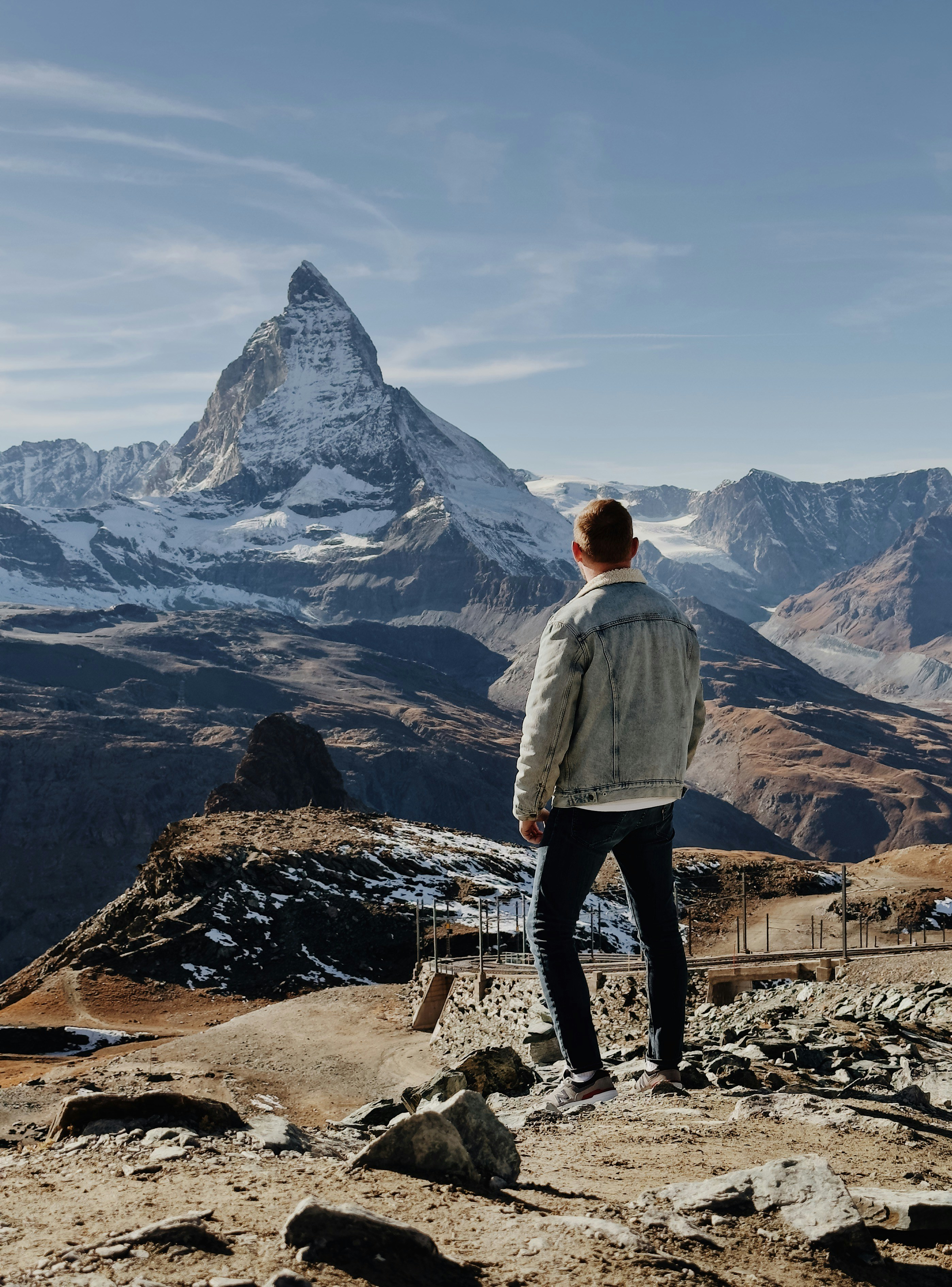 a man standing on a rocky hill looking at a mountain