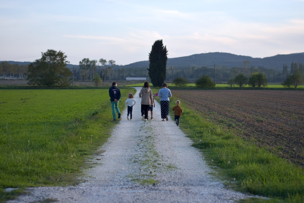 a group of people walking on a dirt road in a field