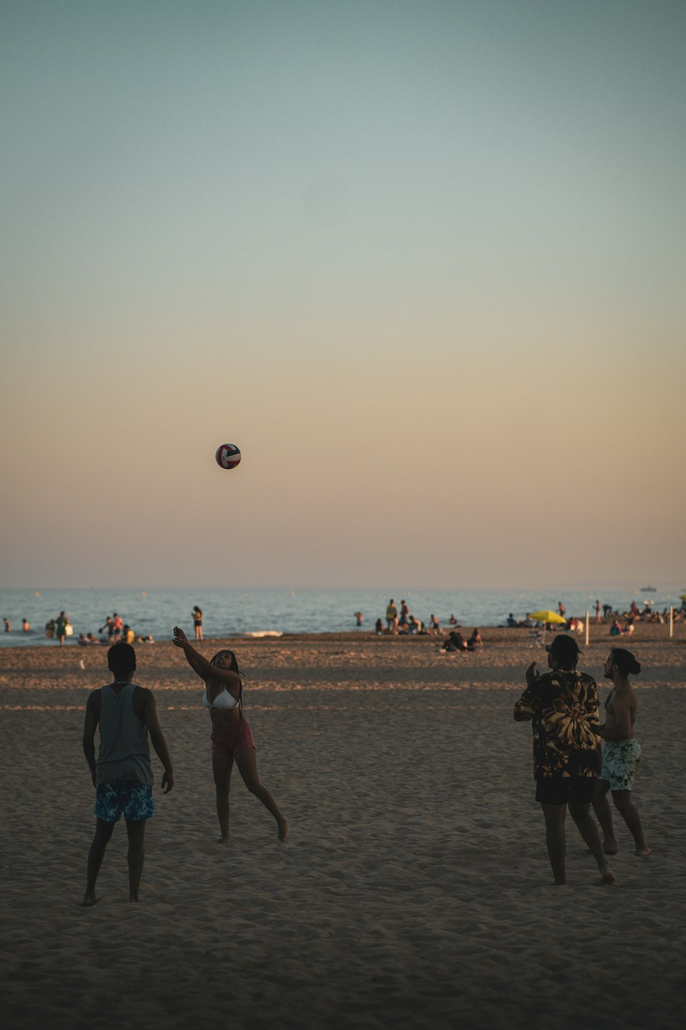 des gens qui jouent avec un ballon sur une plage