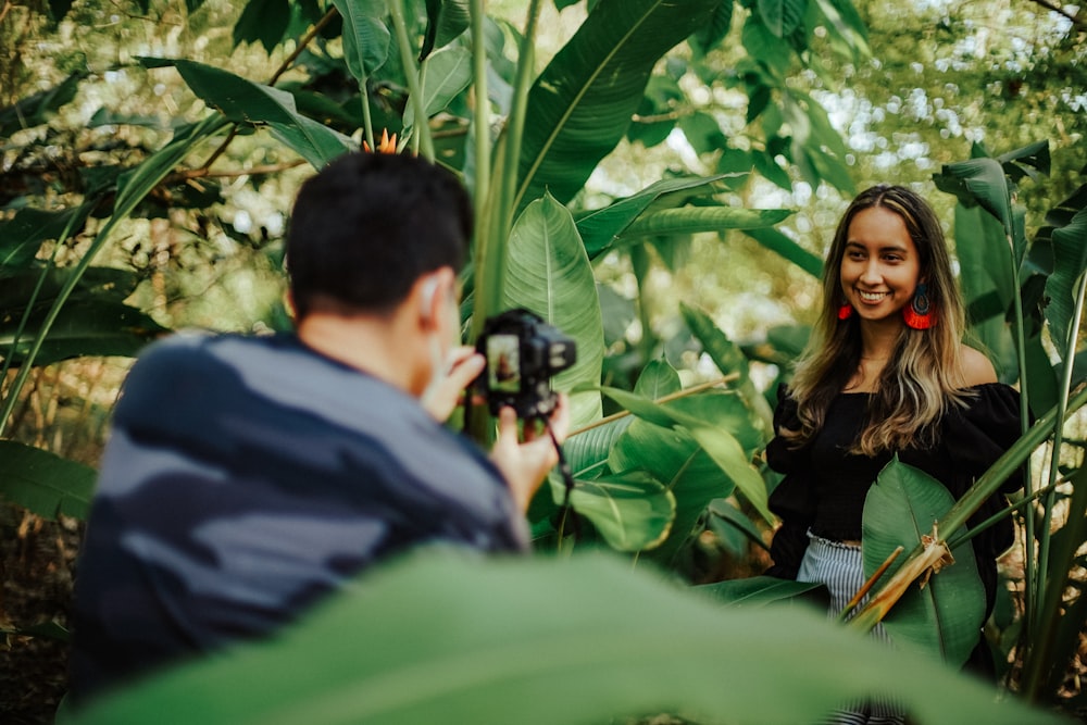 a man taking a picture of a woman in a garden