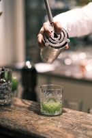 a person holding a knife over a glass of liquid