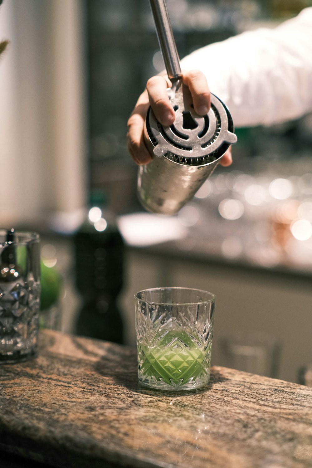 a person holding a knife over a glass of liquid