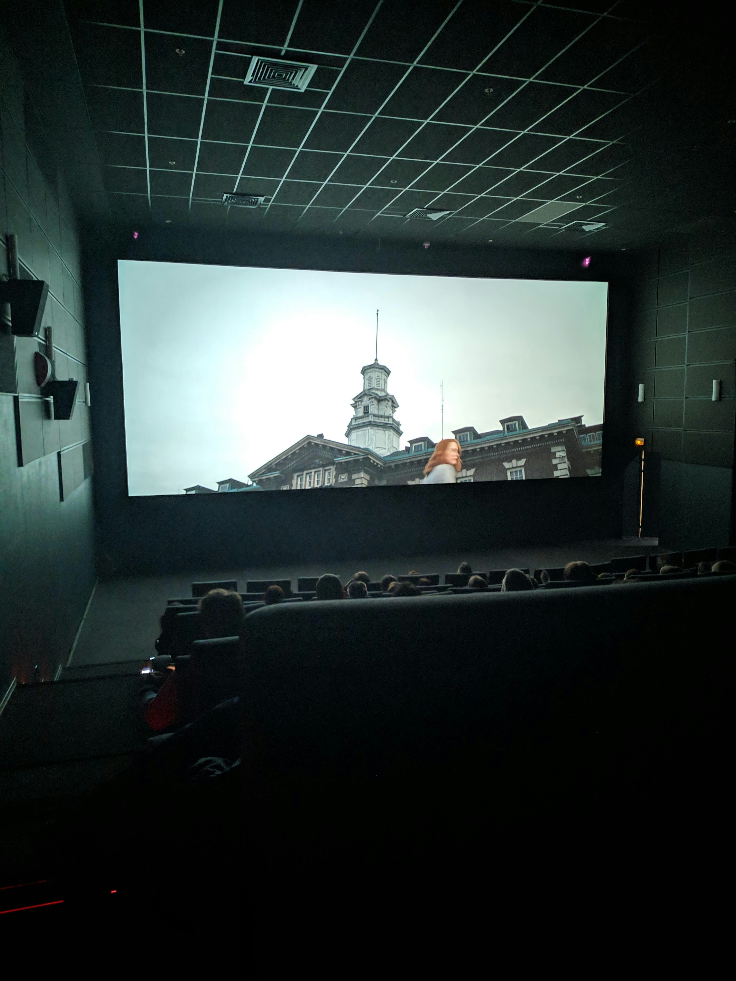 Home cinema setup with large bright screen showing movie, dark atmospheric room