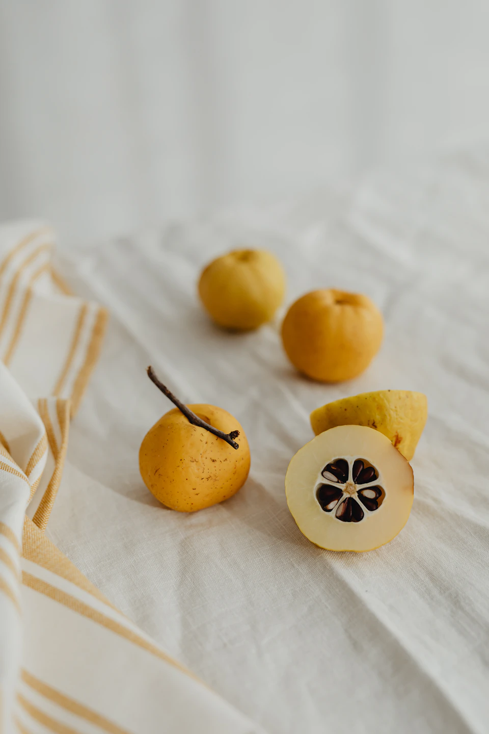 White tablecloth with six yellow pears and two slices of fruit in arrangement