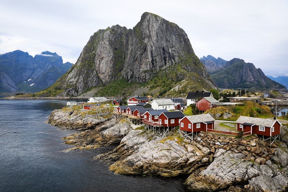 a group of houses by a body of water with mountains in the background with Lofoten in the background
