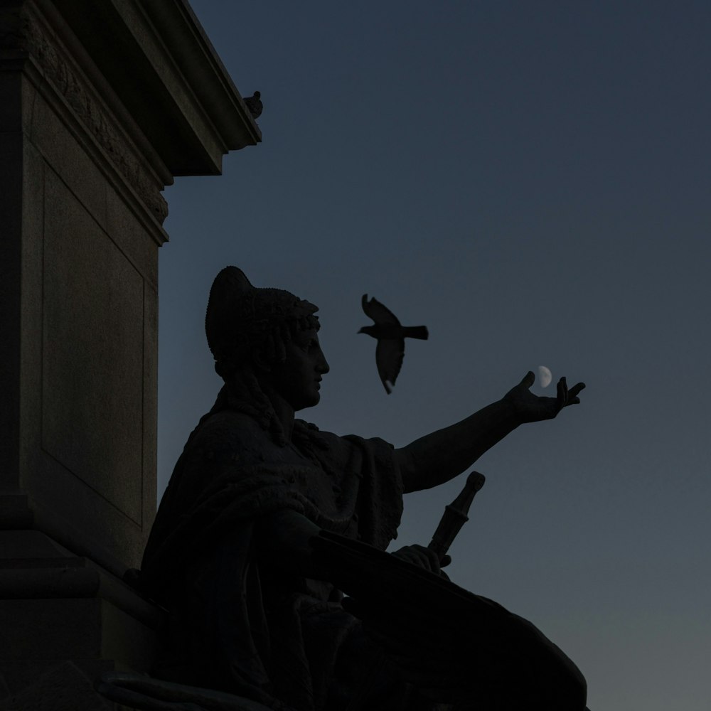 uma estátua de uma pessoa segurando um pássaro