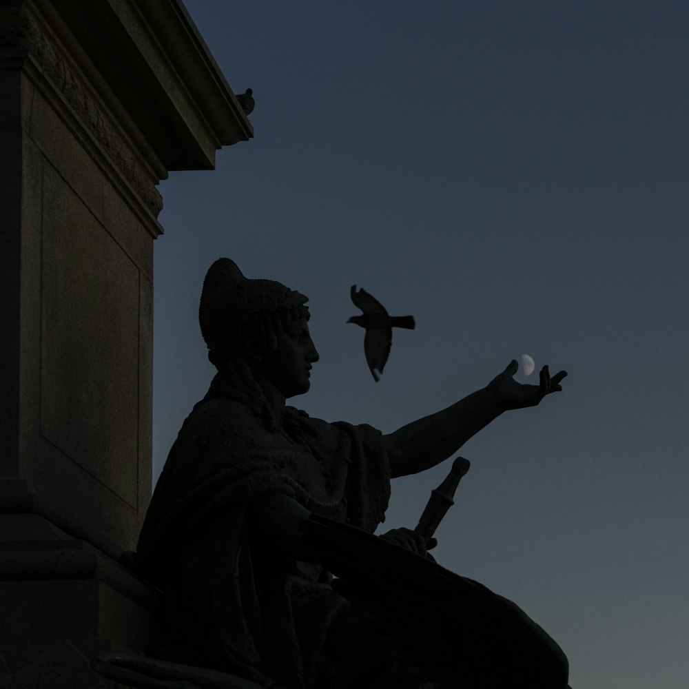 eine Statue einer Person, die einen Vogel hält