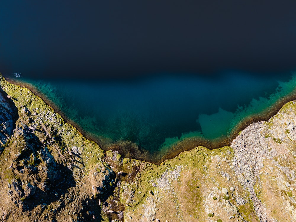 a rocky cliff with a body of water in the background