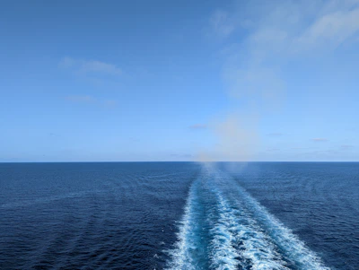 A vintage photograph of the first Earth Ocean Shipping vessel at sea under a clear blue sky.