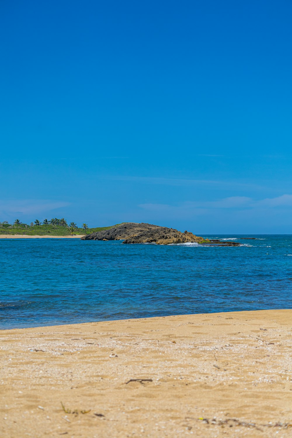 a sandy beach with a small island in the distance