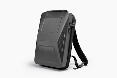 Modern laptop backpack with clean lines hanging on a bike handlebar in an urban park
