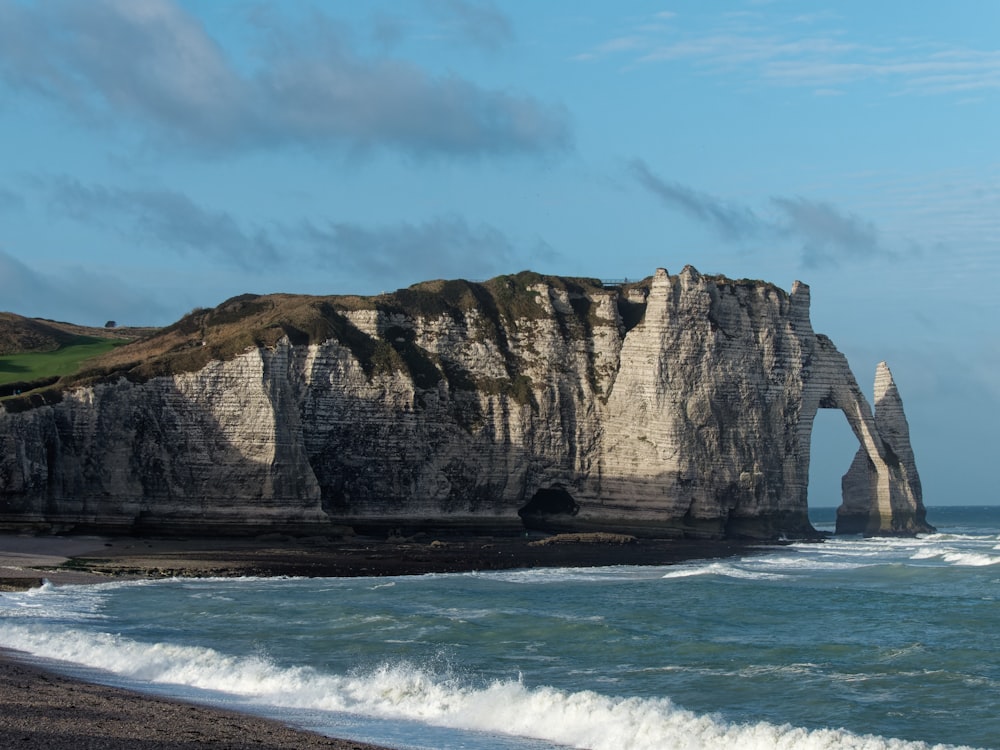 a cliff with a cave in the middle of the water