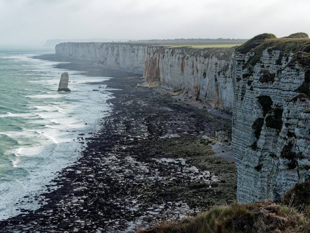 a cliff side with a body of water below with Bempton Cliffs in the background