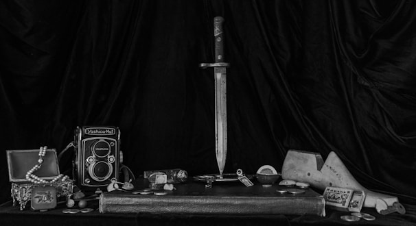 A still life arrangement of vintage items resting on a black surface with moody shadows.