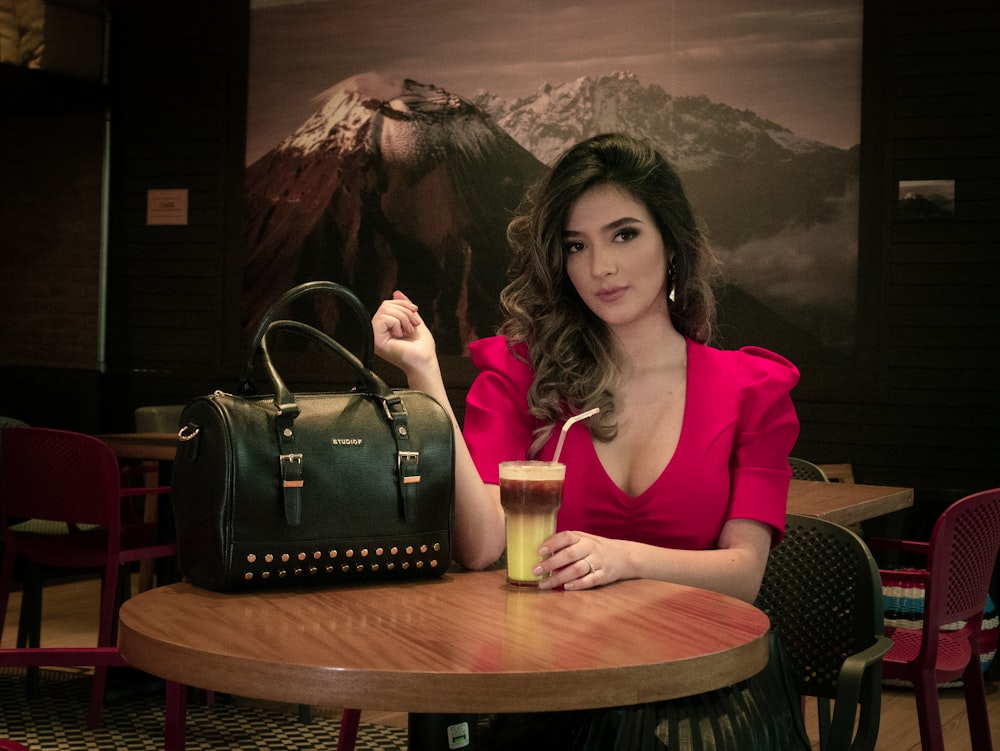 a person sitting at a table with a drink and a bag