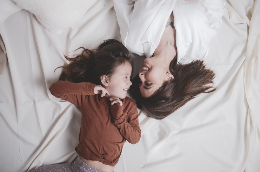 a woman and a child lying on a bed