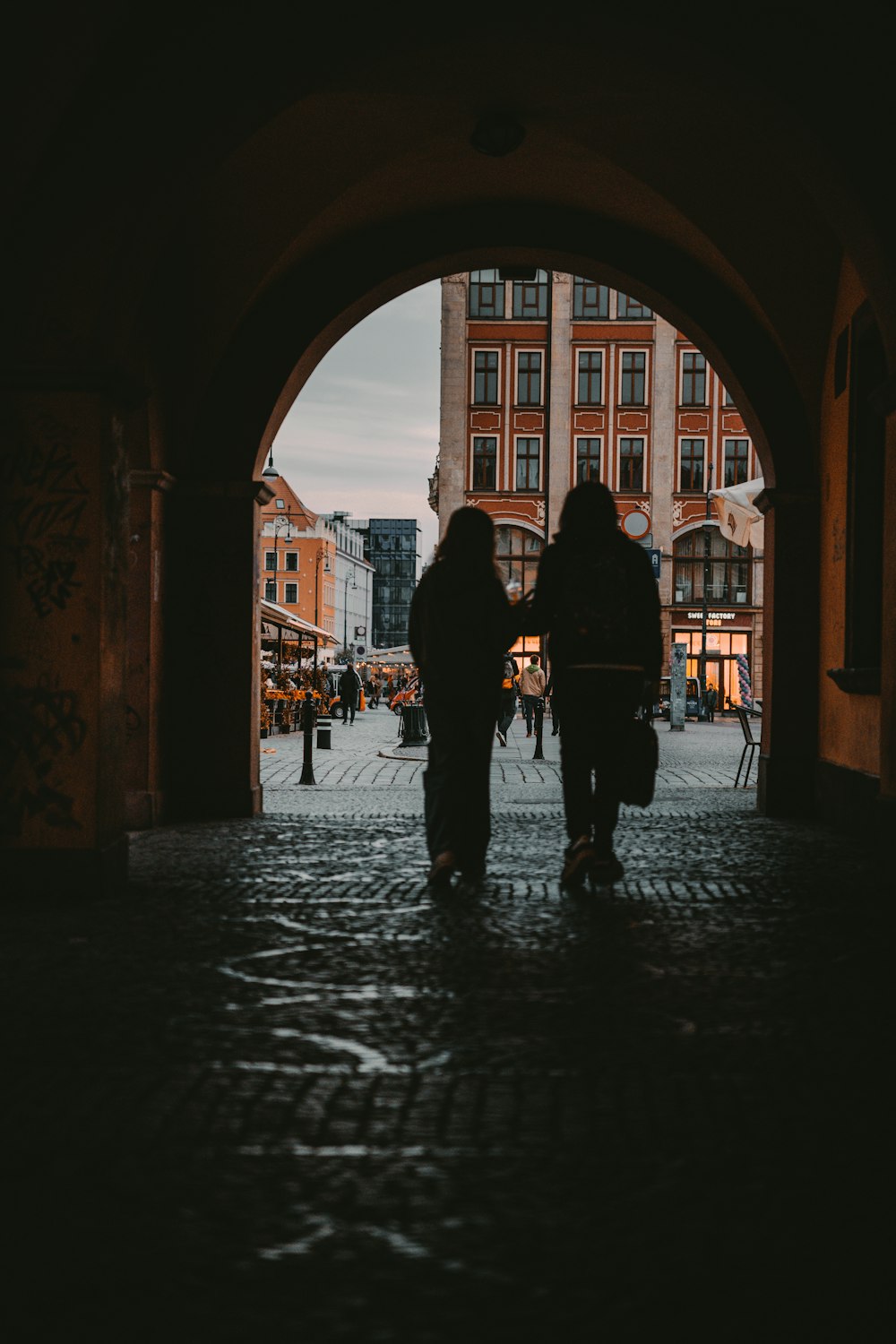 a couple of people walking under a large archway