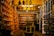 A shop interior filled with various cultural and decorative items, including masks, statues, and bowls displayed on shelves and tables. The shelves are organized with items displayed in an orderly fashion, and there is dim lighting creating a cozy atmosphere.