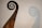 An intricately carved wooden spiral feature, reminiscent of a ship’s prow or ornamental decoration, casts a shadow on a plain backdrop. The carvings display detailed and flowing Celtic knot patterns.