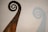 An intricately carved wooden spiral feature, reminiscent of a ship’s prow or ornamental decoration, casts a shadow on a plain backdrop. The carvings display detailed and flowing Celtic knot patterns.