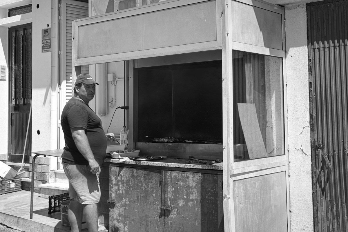 A volunteer arranges snacks and drinks on a table outside a youth sports concession stand.