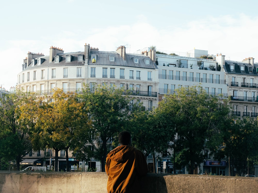 a man standing in front of a building with trees in front of it