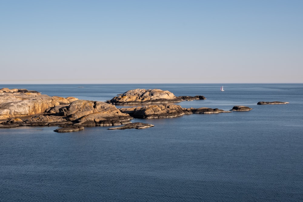 a rocky shoreline with a sailboat