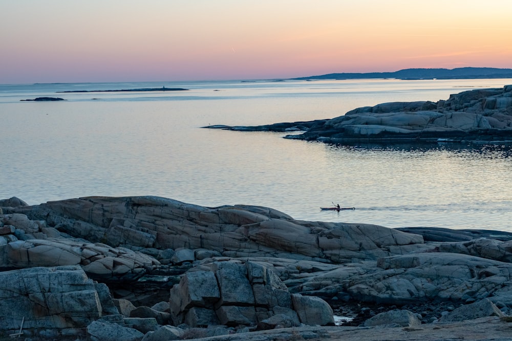 a rocky beach with a body of water in the background