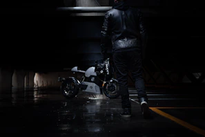 Urban model wearing a premium leather jacket walking through city streets at dusk.