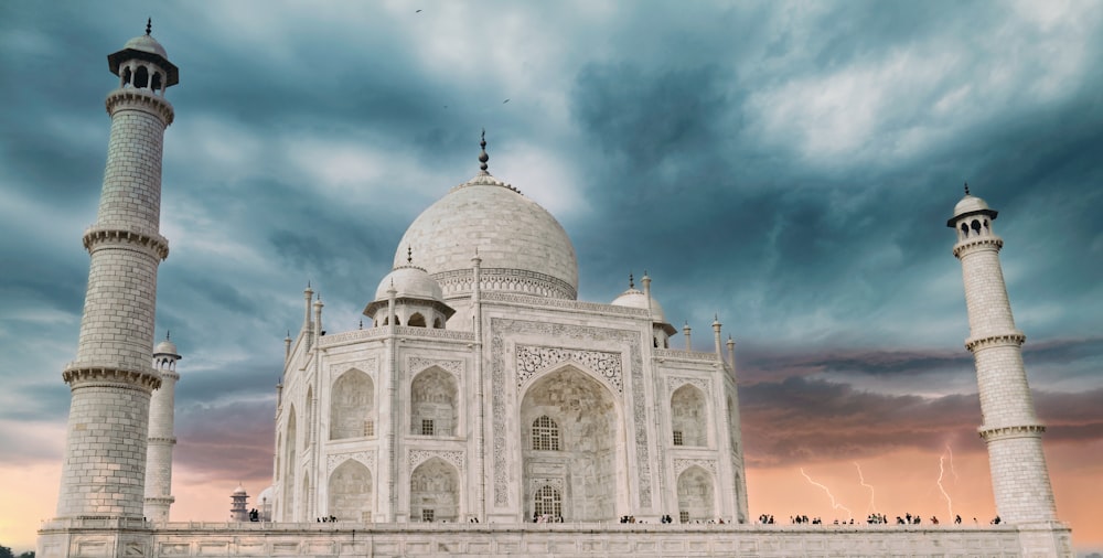 a large white building with towers with Taj Mahal in the background