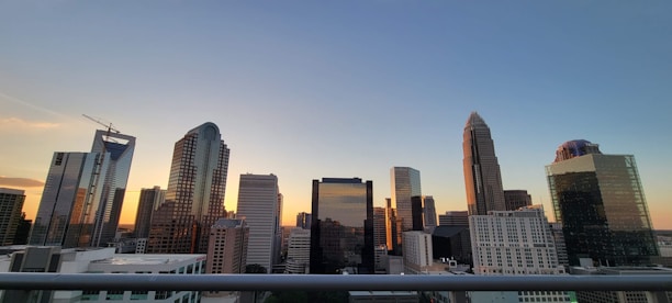 A city skyline at sunset with modern residential and commercial buildings reflecting warm light.