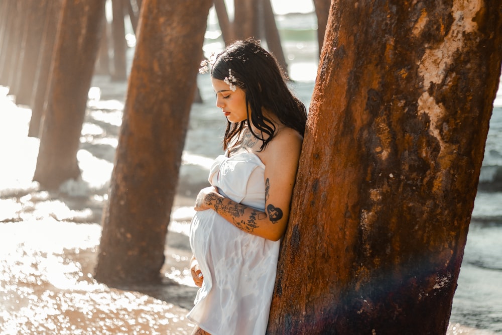 a person in a white dress standing next to a tree