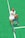 A person wearing a white sports outfit is sitting on a bright green tennis court. The individual has their eyes closed and appears relaxed. They are holding a tennis racket in one hand, and wearing gray sneakers and blue patterned socks.