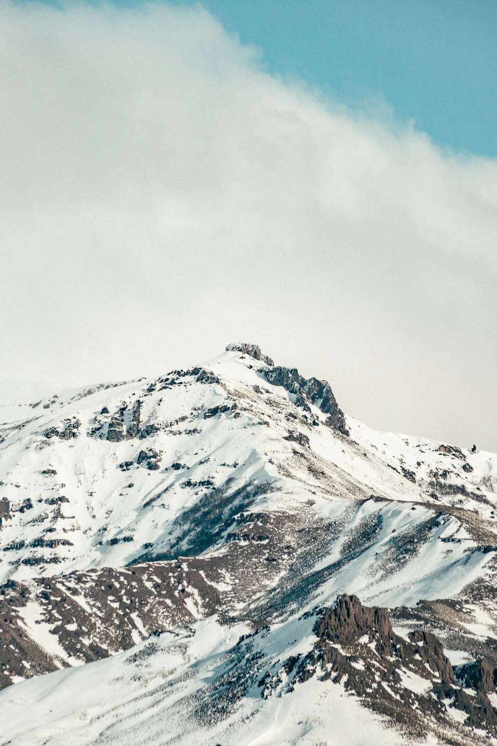 a snowy mountain with clouds