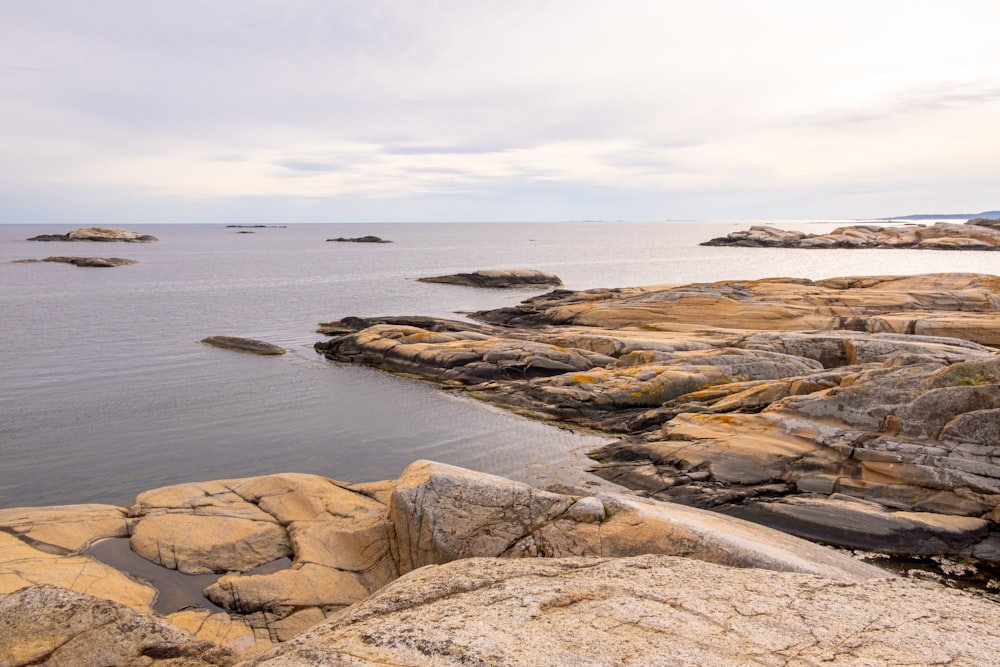 a rocky beach with a body of water in the background