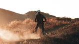A rugged dirt bike speeding through a dusty trail at sunset.