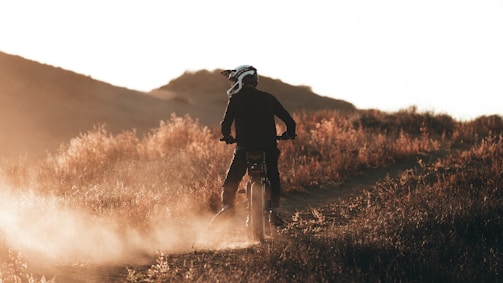 A rugged dirt bike tearing through a muddy trail at sunset.