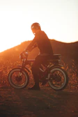 A rider wearing a helmet smiling while waiting on a sleek motorcycle at sunset.