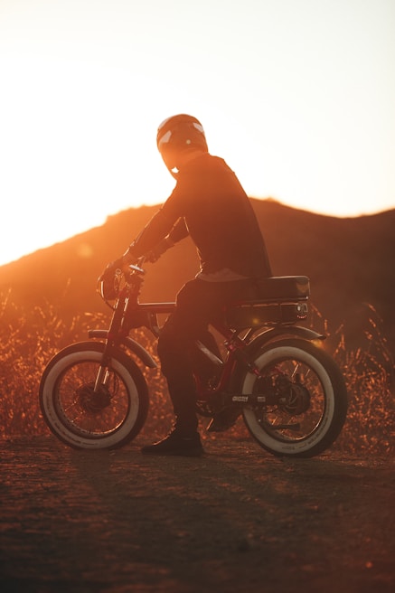 Close-up of a rider’s helmet and goggles, reflecting the fiery orange glow of the setting sun