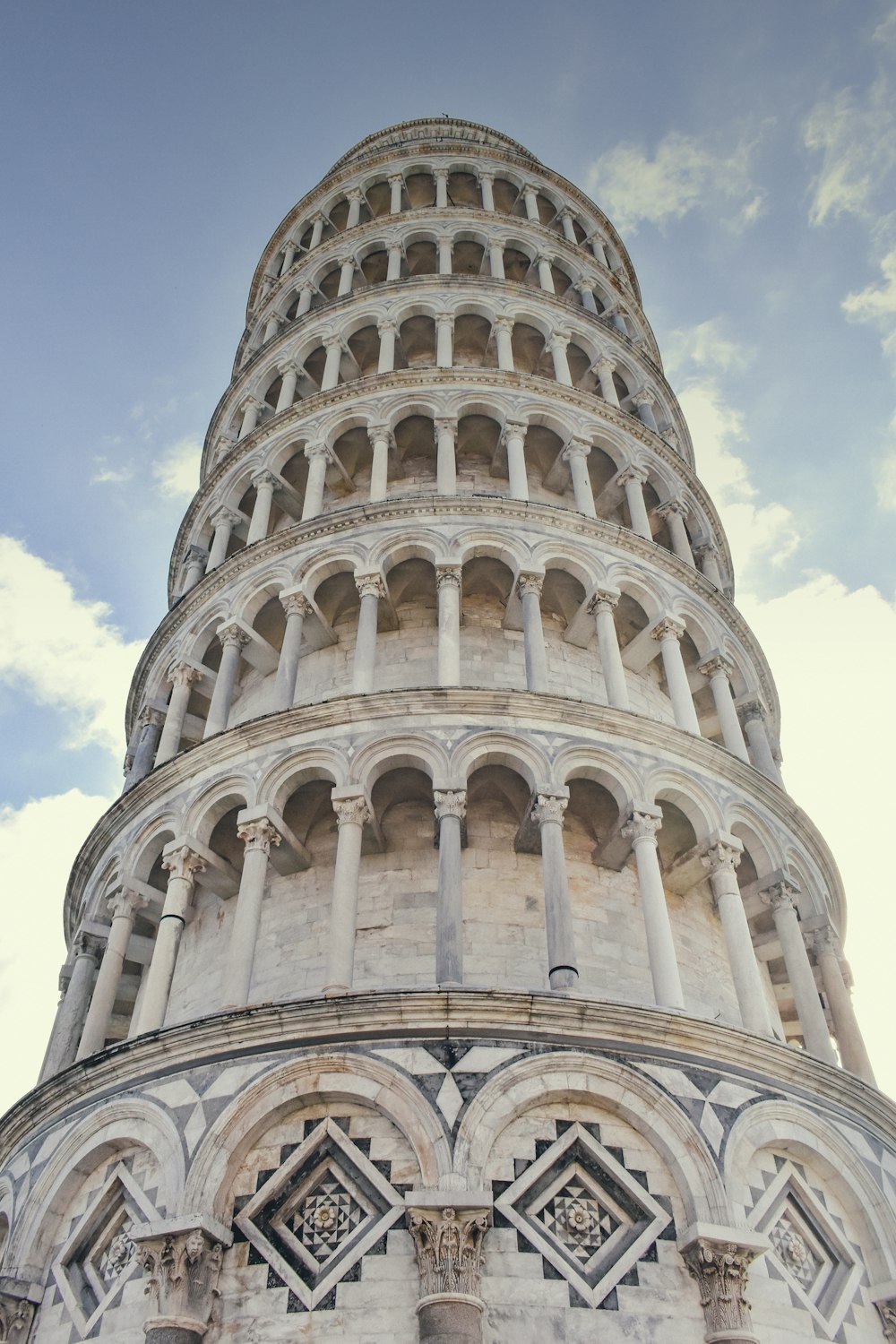 a large stone building with Leaning Tower of Pisa in the background
