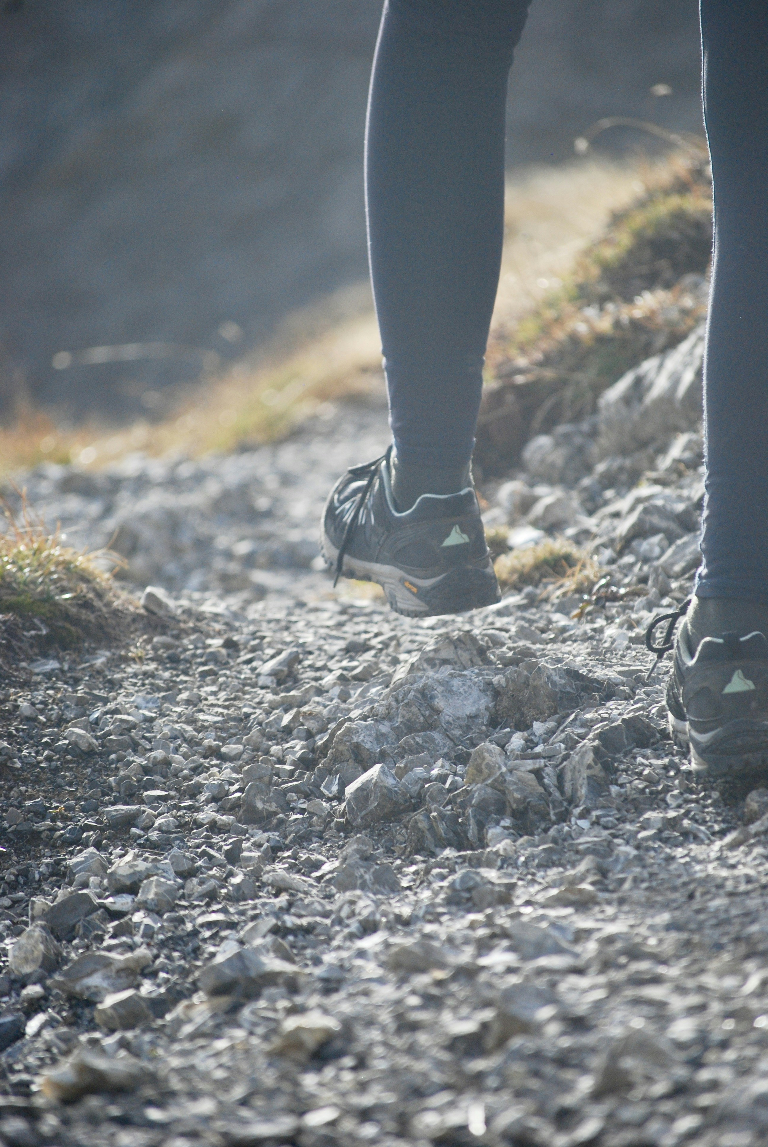 a person's legs in a shoe on a rocky surface