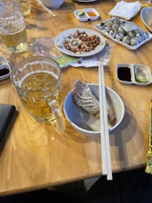 A colorful spread of Qingdao street food including seafood, dumplings, and Tsingtao beer on a rustic wooden table.