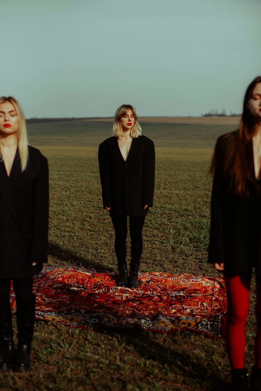 a group of women standing on a field with a red blanket