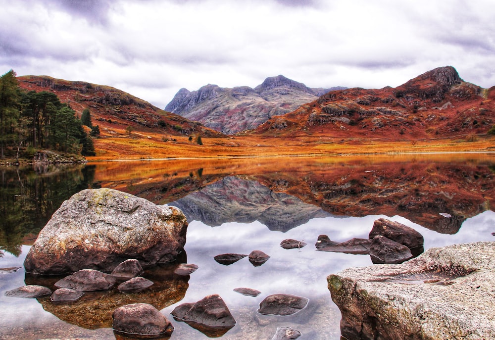 a lake with rocks and mountains in the background