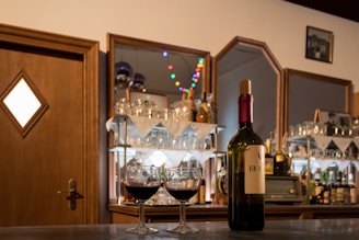 Close-up of wine glasses and bottles on a wooden table in a cozy setting