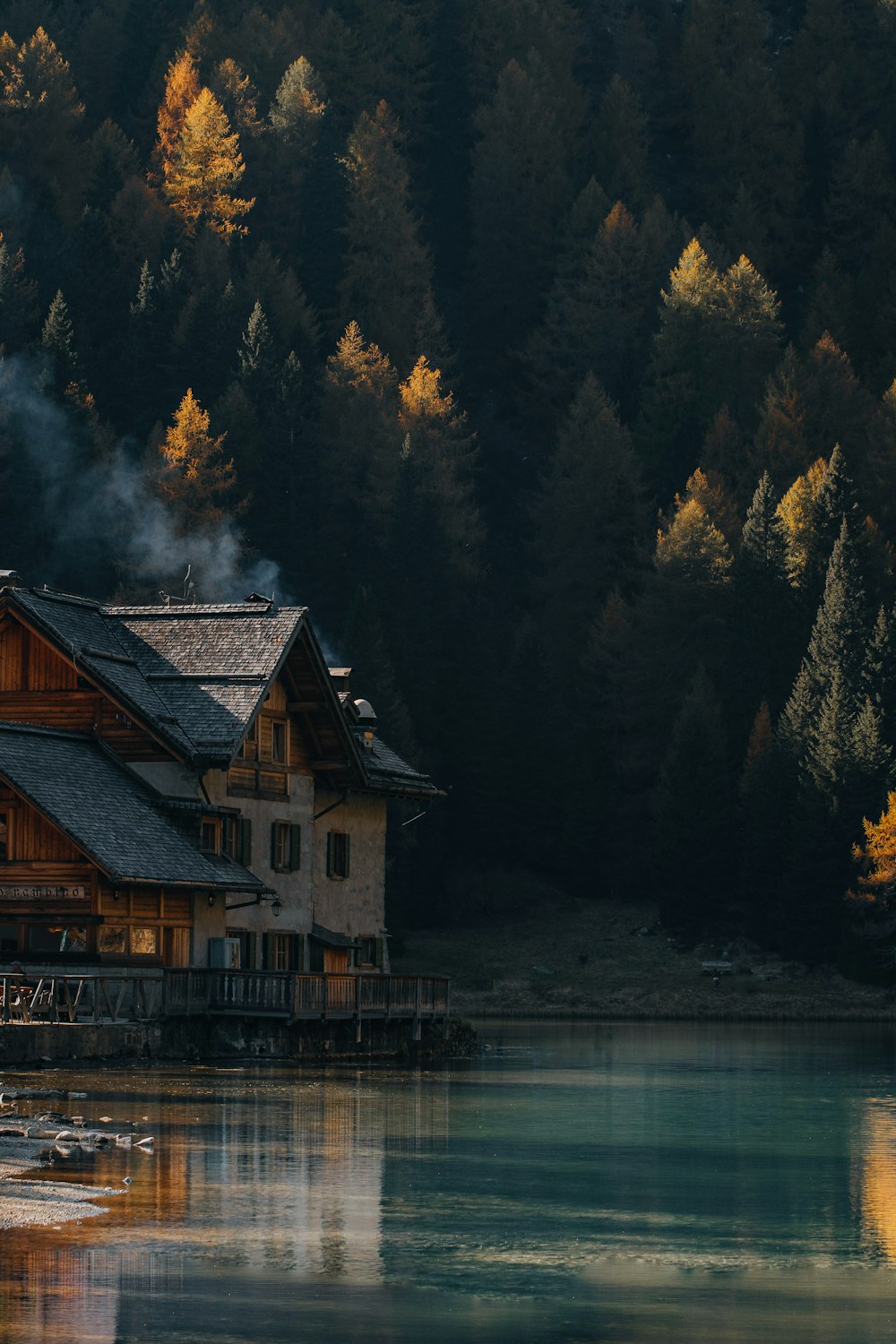 a house on a dock by a lake with trees in the background