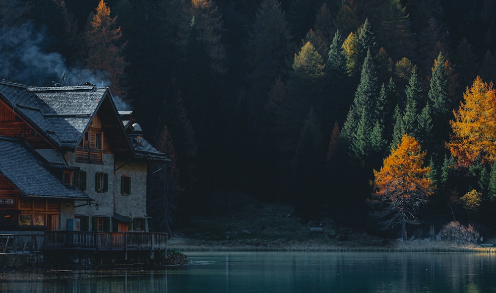 a house on a dock by a lake with trees and mountains in the background