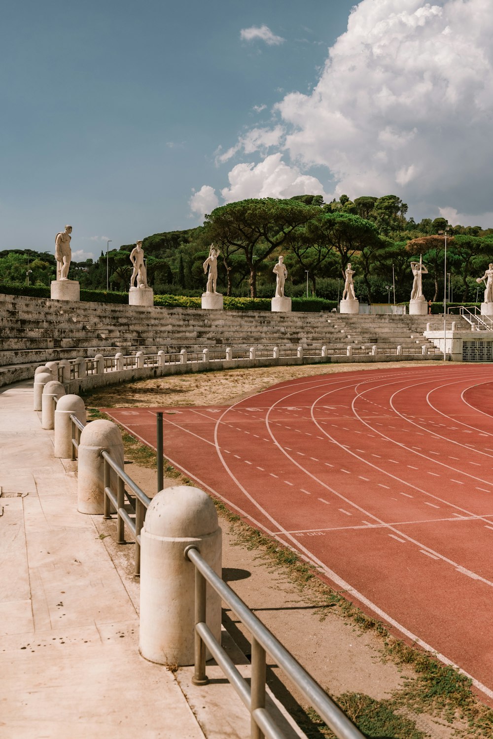 a red tiled road with statues on either side of it